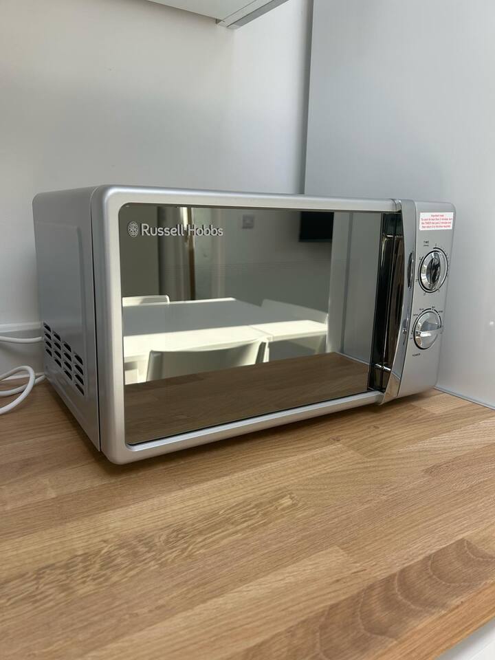 Reflective microwave on wood counter in clean, modern kitchen.