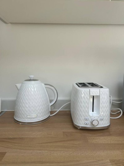Stylish kettle and toaster set on wood counter with clean white walls.