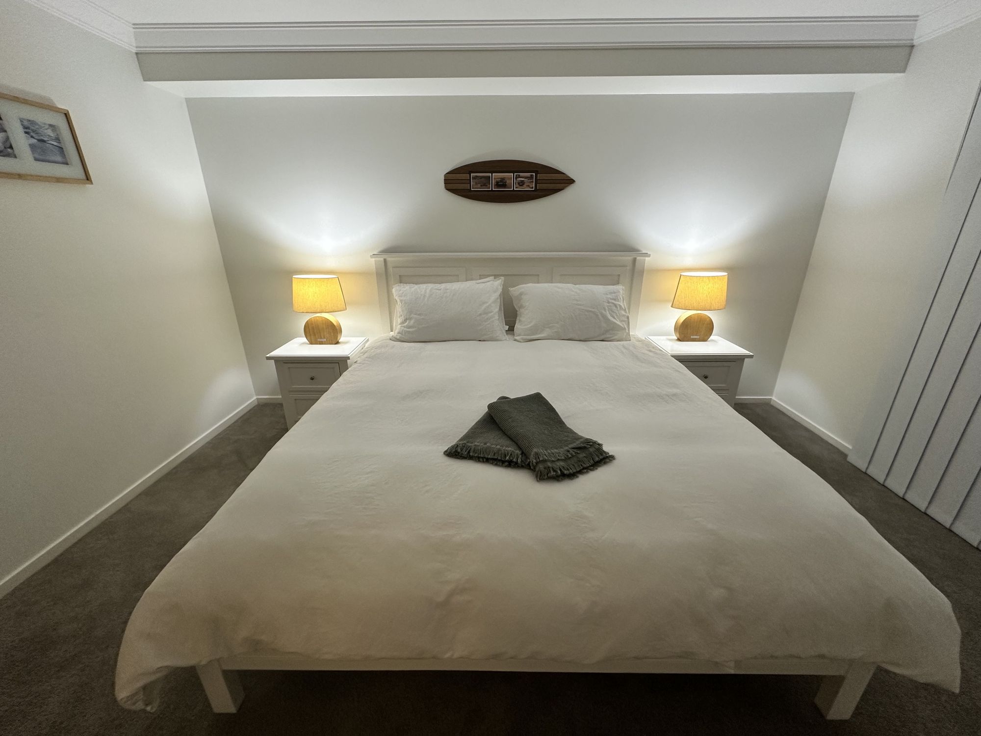 Cozy, minimalist bedroom with warm lighting and a plush king bed