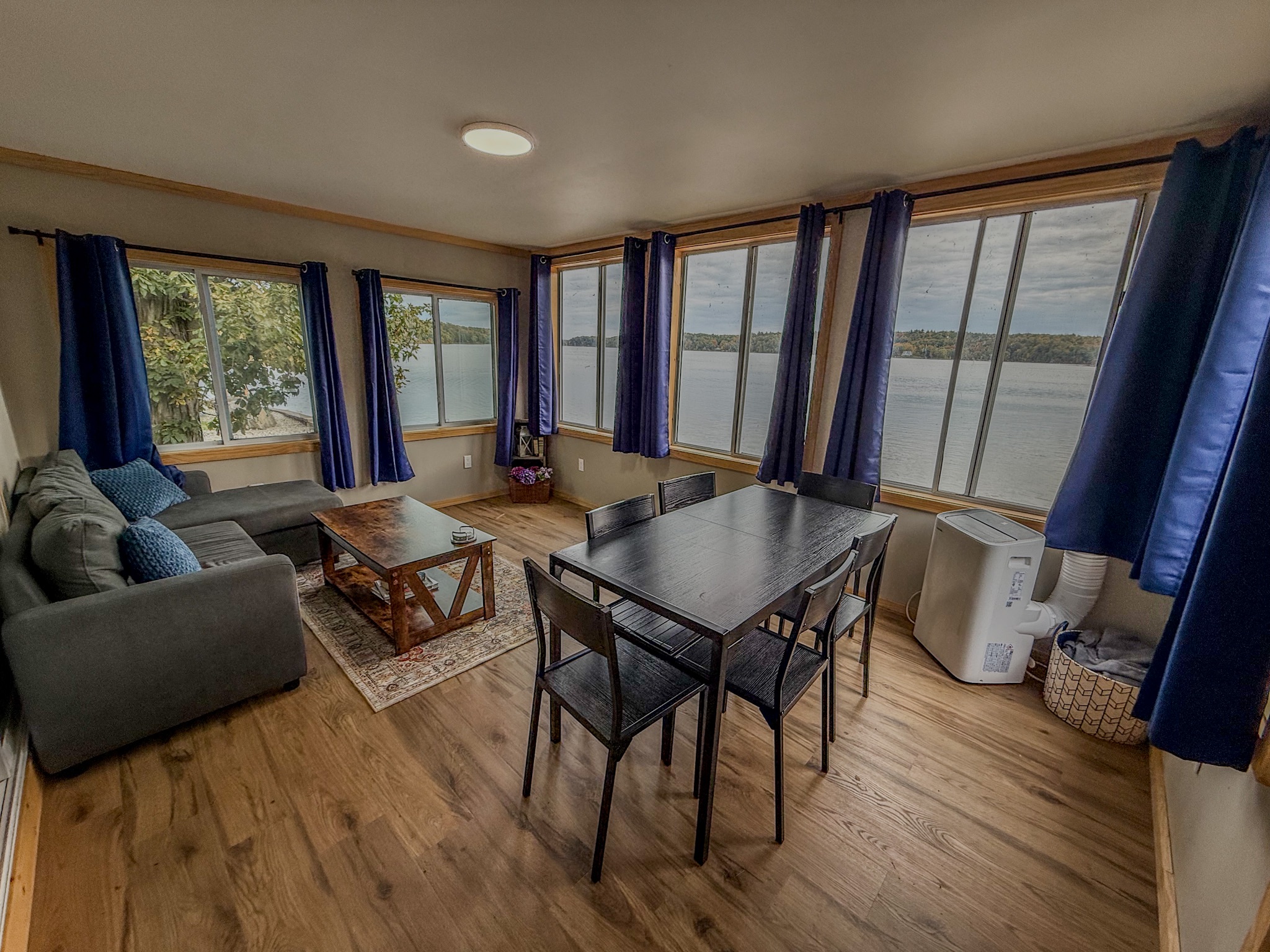 Bright waterfront living room with wraparound views and dining space