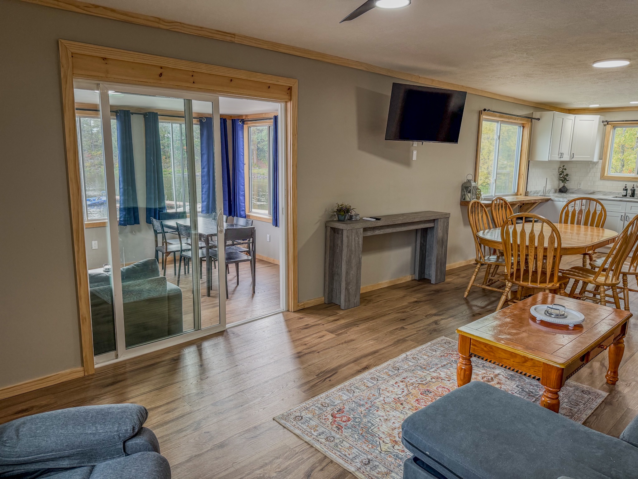 Bright open living area with dining space, TV, and sunroom views