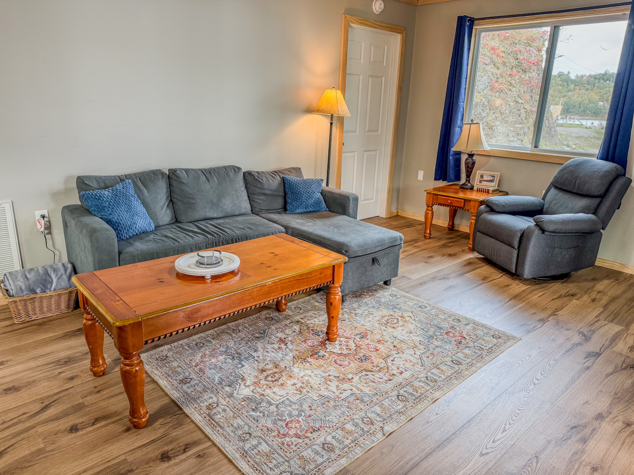 Cozy, sunlit living room with sectional, recliner, and scenic window views
