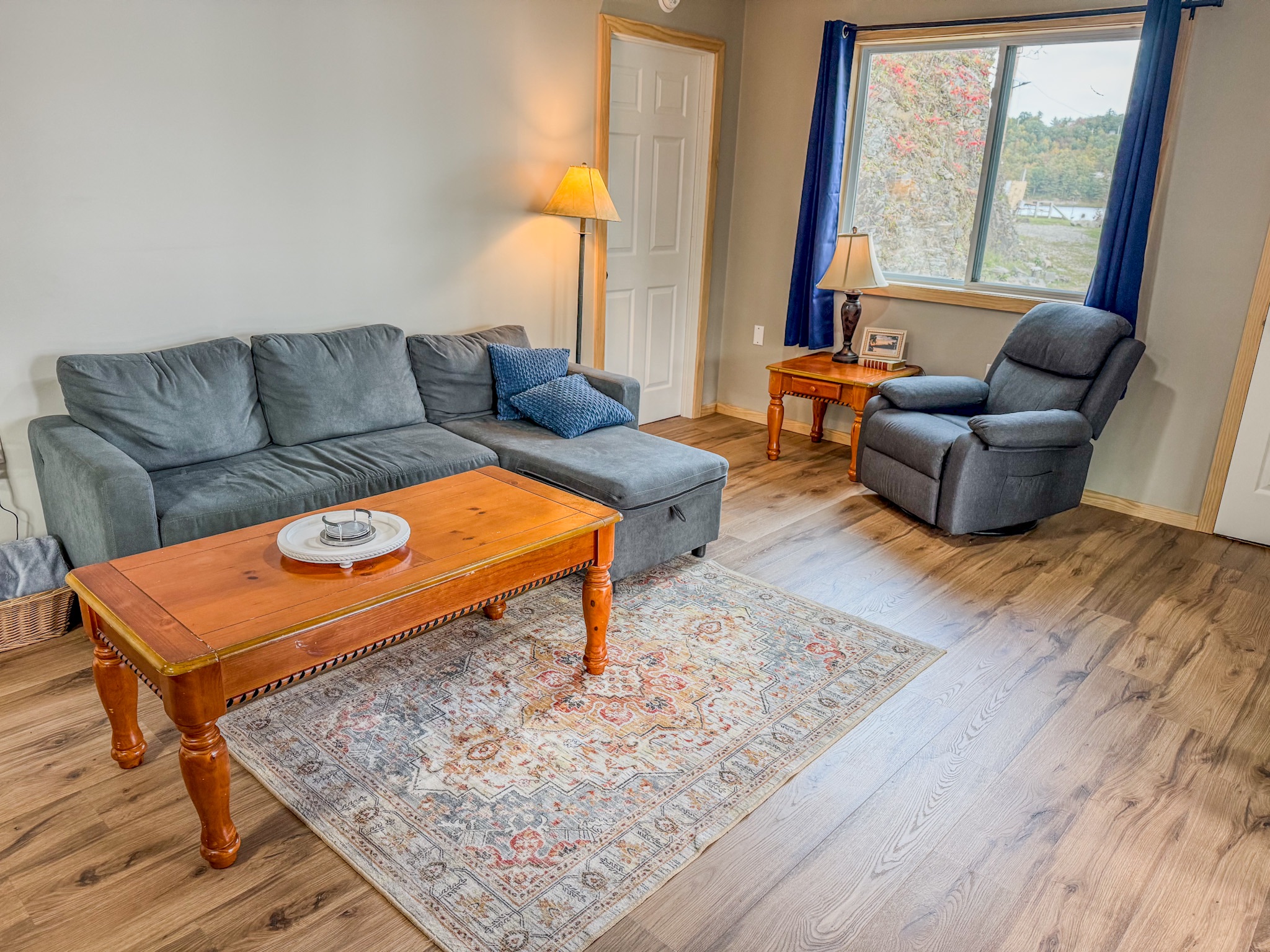 Bright, cozy living room with sectional, recliner, and scenic window views