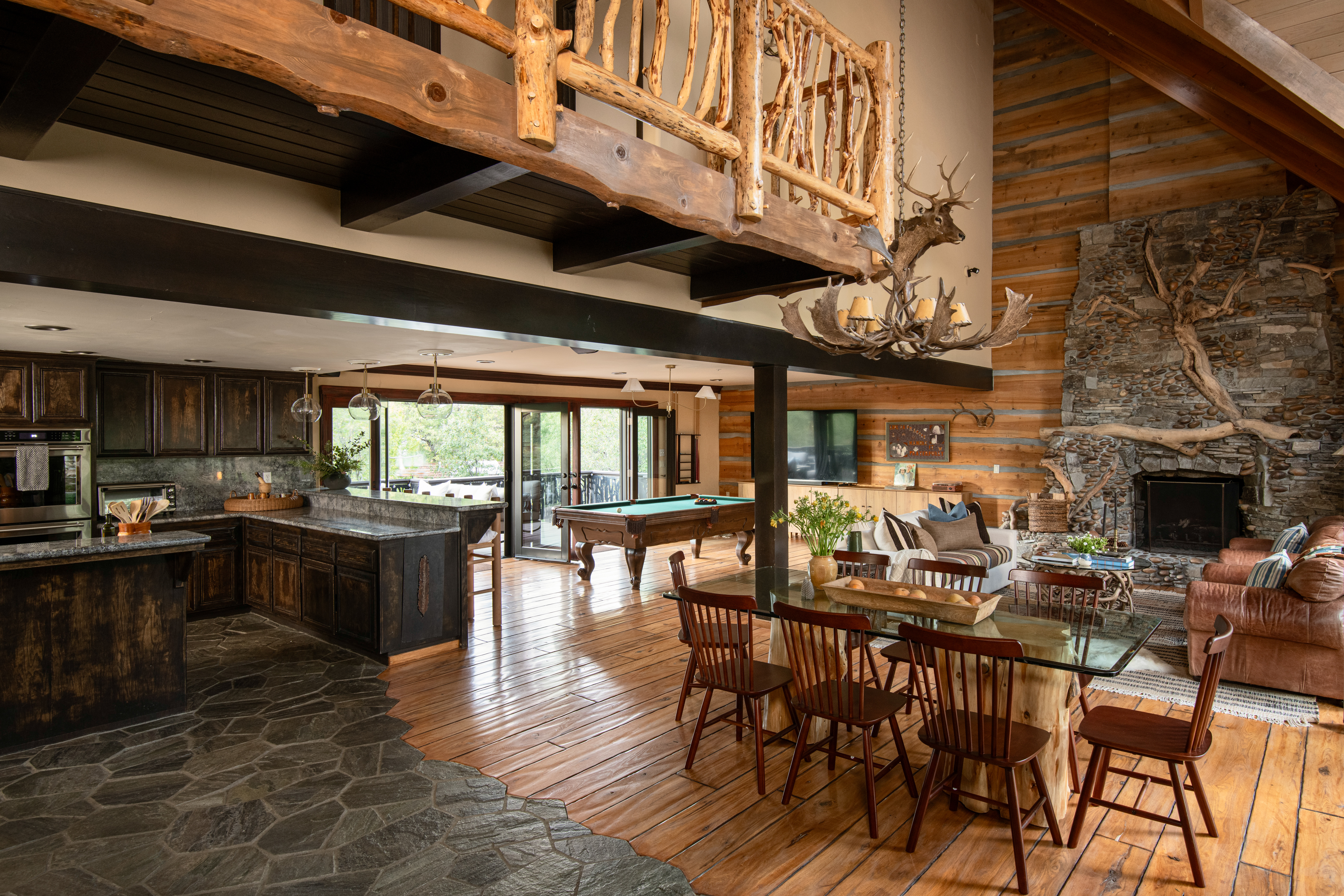 Rustic great room with stone fireplace, pool table, and open kitchen