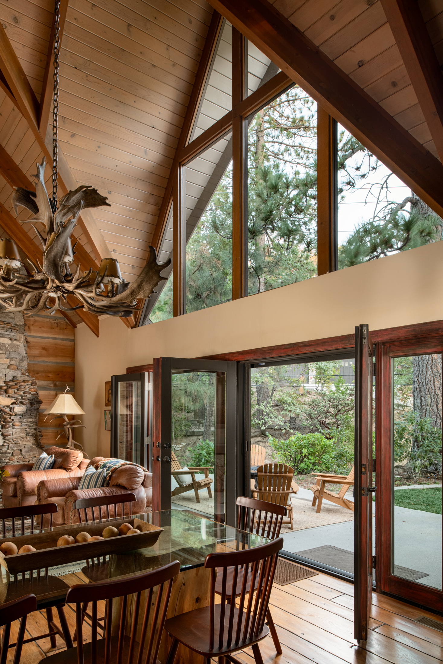 Vaulted lodge-style great room with forest views and patio access