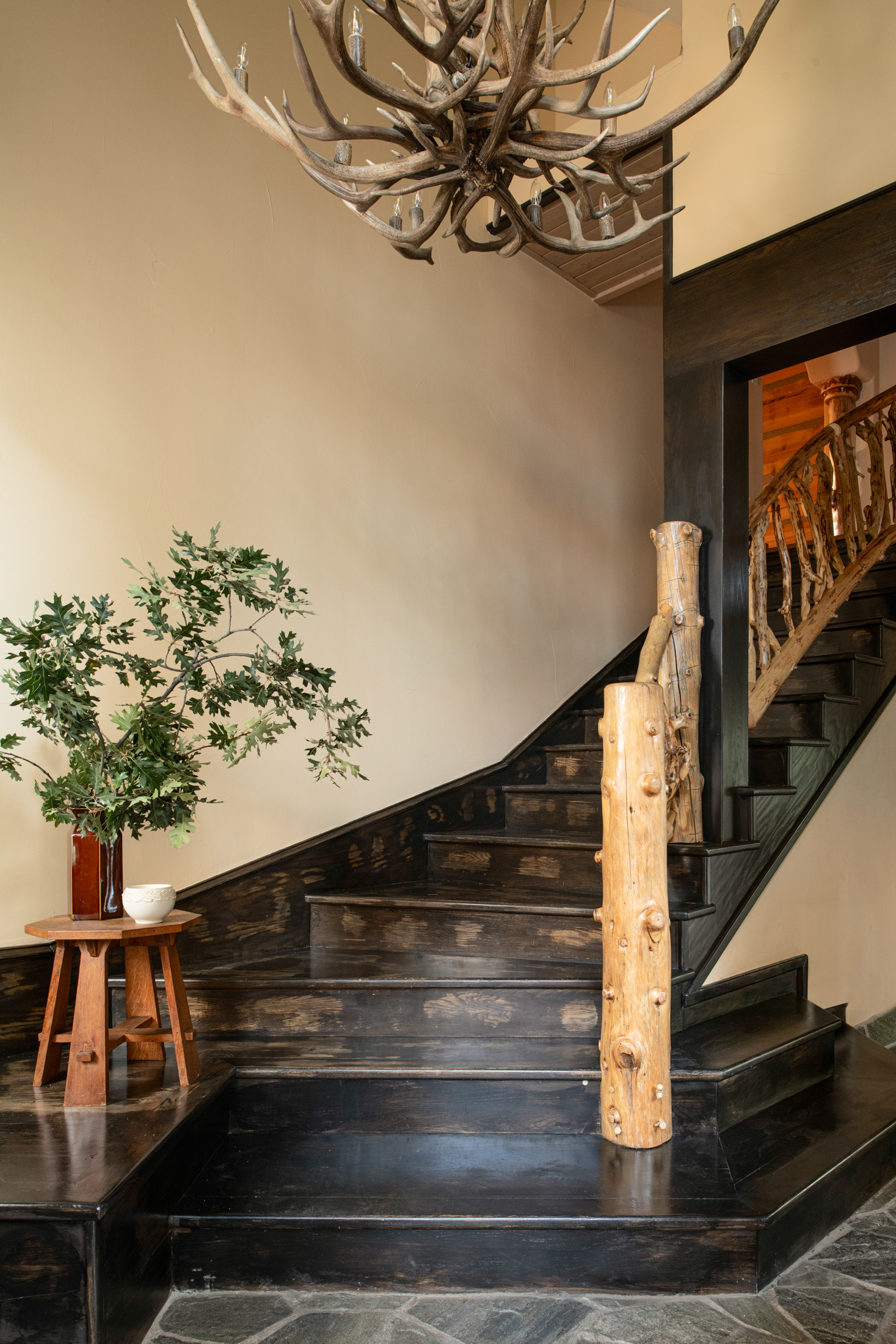 Rustic grand entry with log staircase and stunning antler chandelier