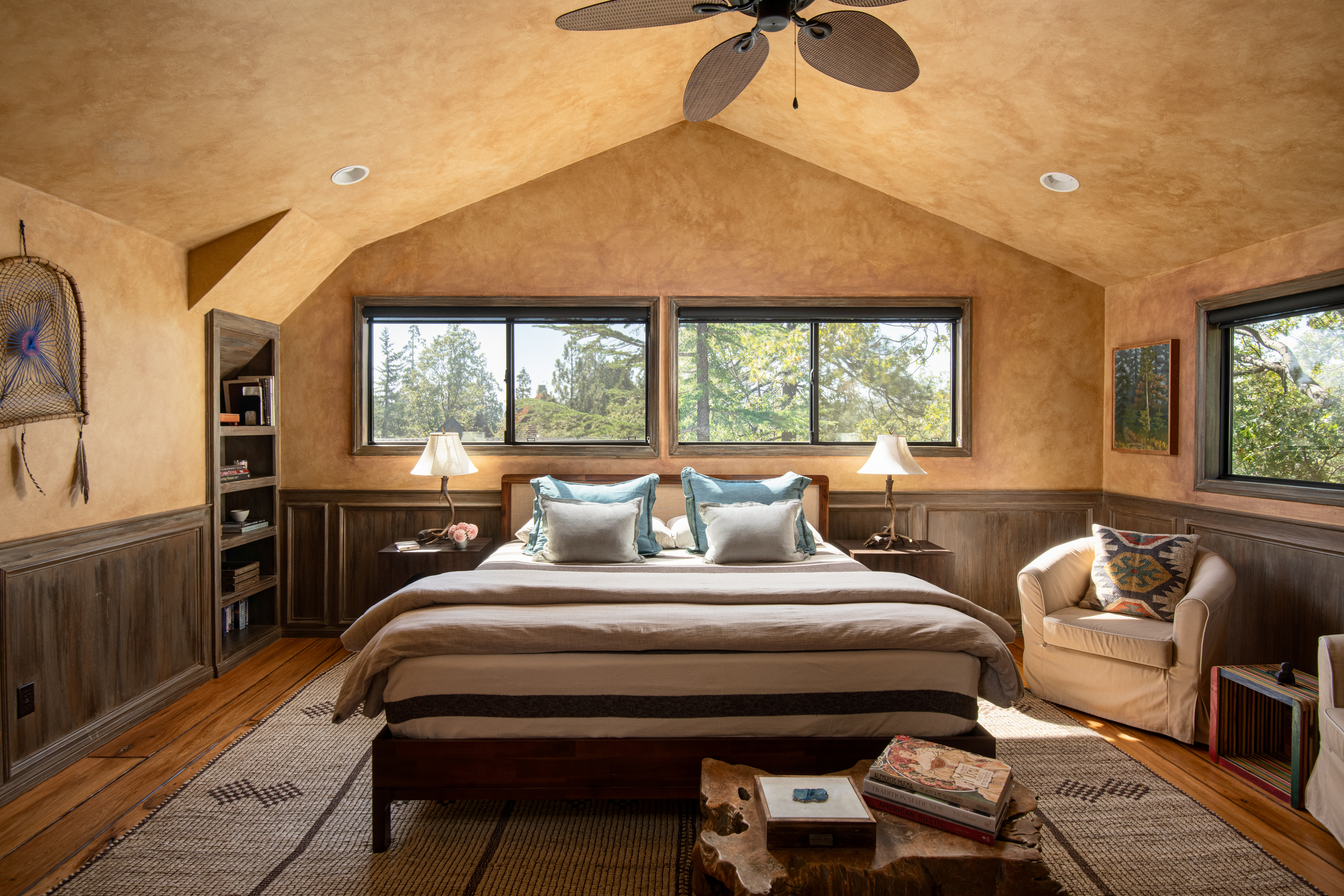 Sunlit rustic king bedroom with vaulted ceilings and peaceful tree views