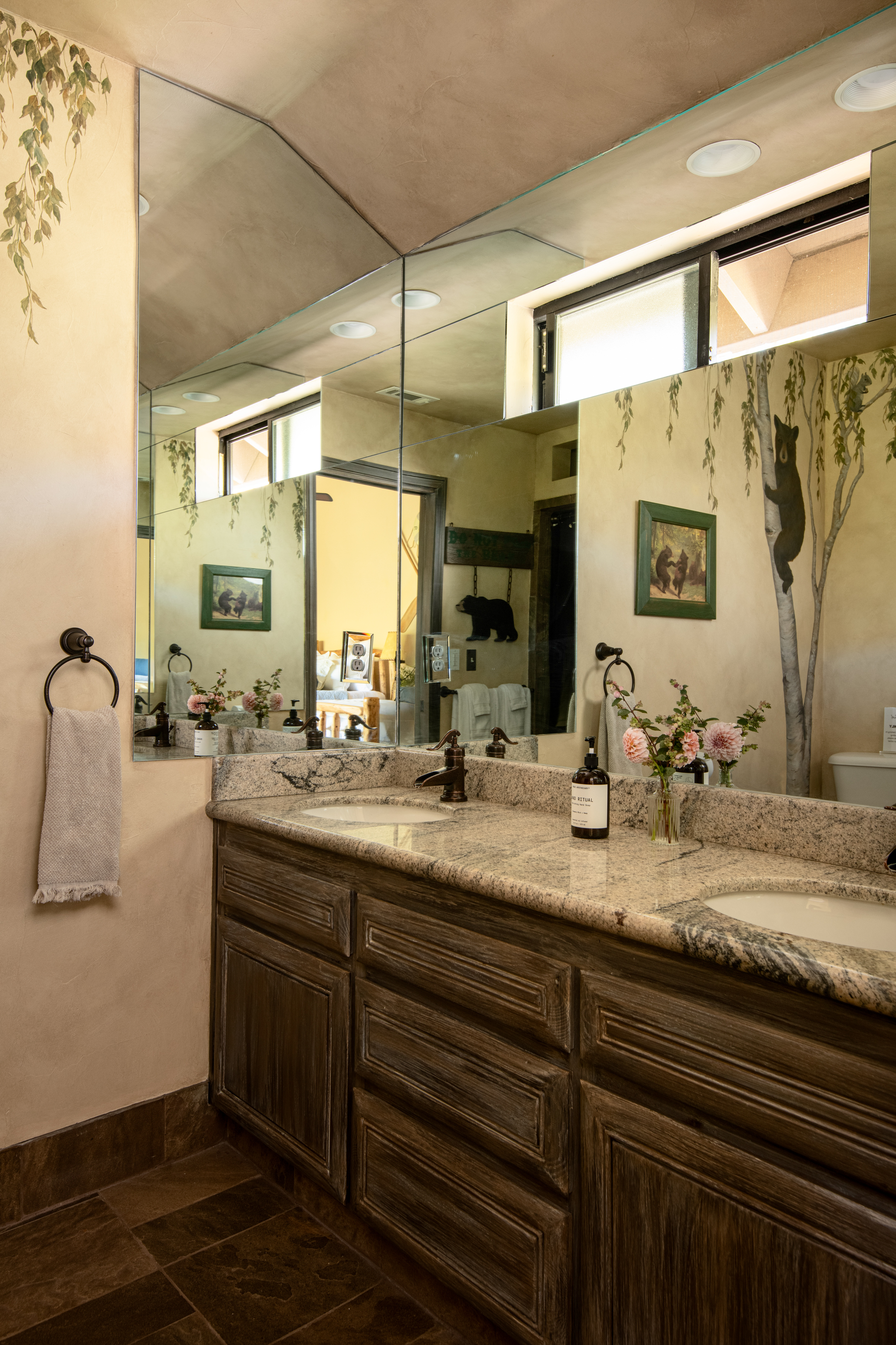 Spacious double vanity bathroom with granite counters and artistic mural walls