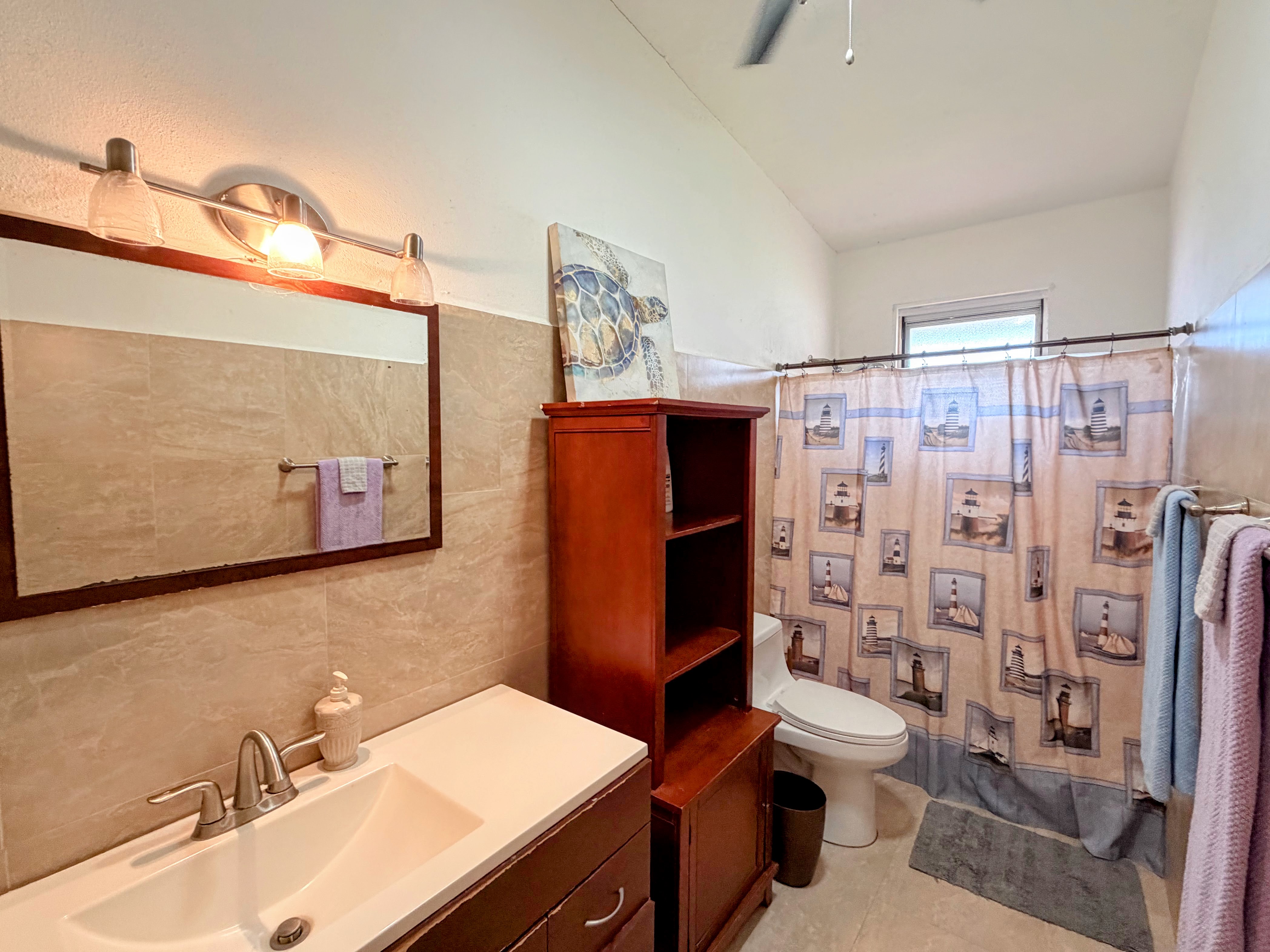 Bright bathroom with high ceilings, extra storage, and a full tub-shower