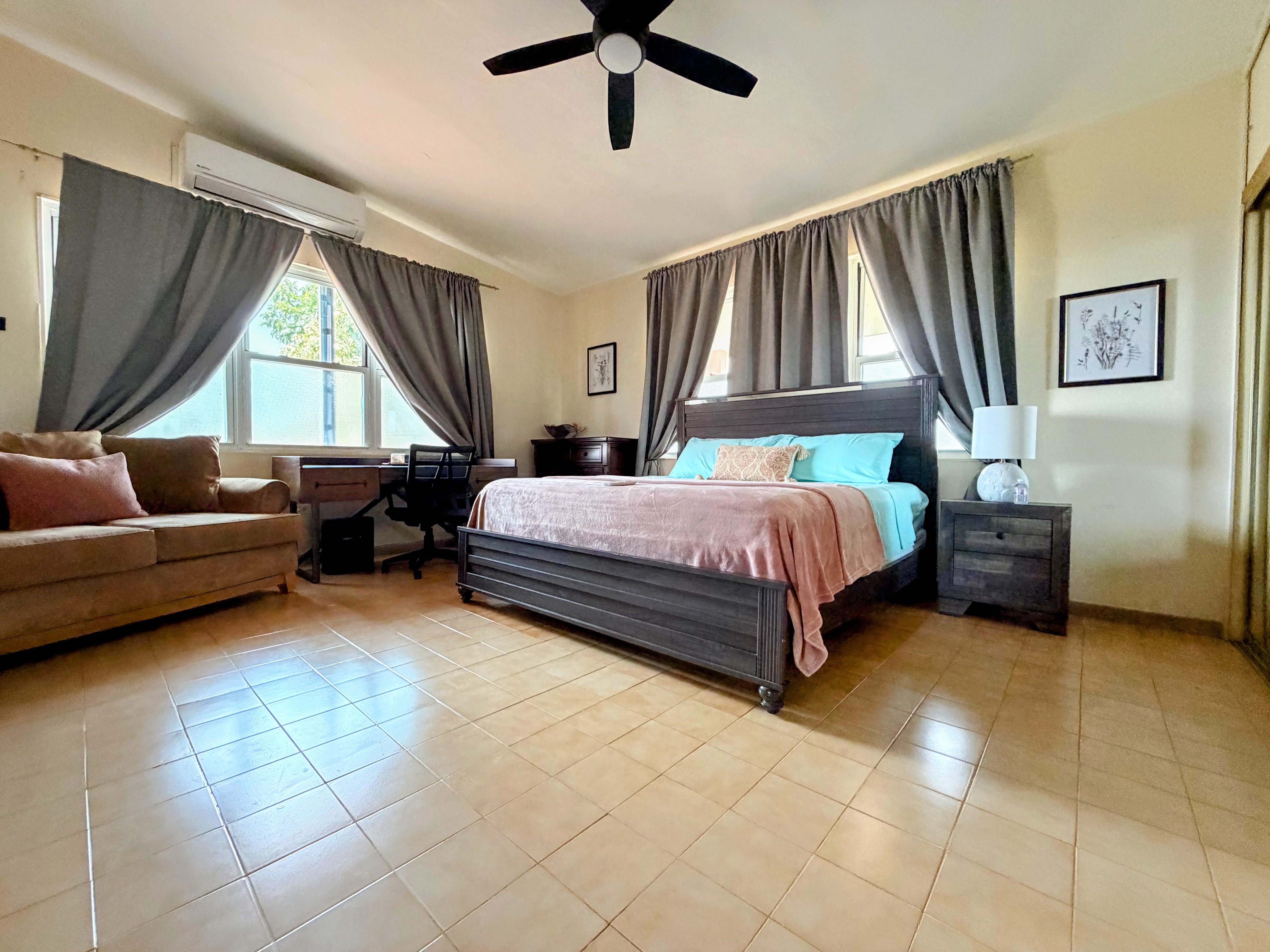 Spacious king bedroom with AC, blackout curtains, loveseat, and workspace