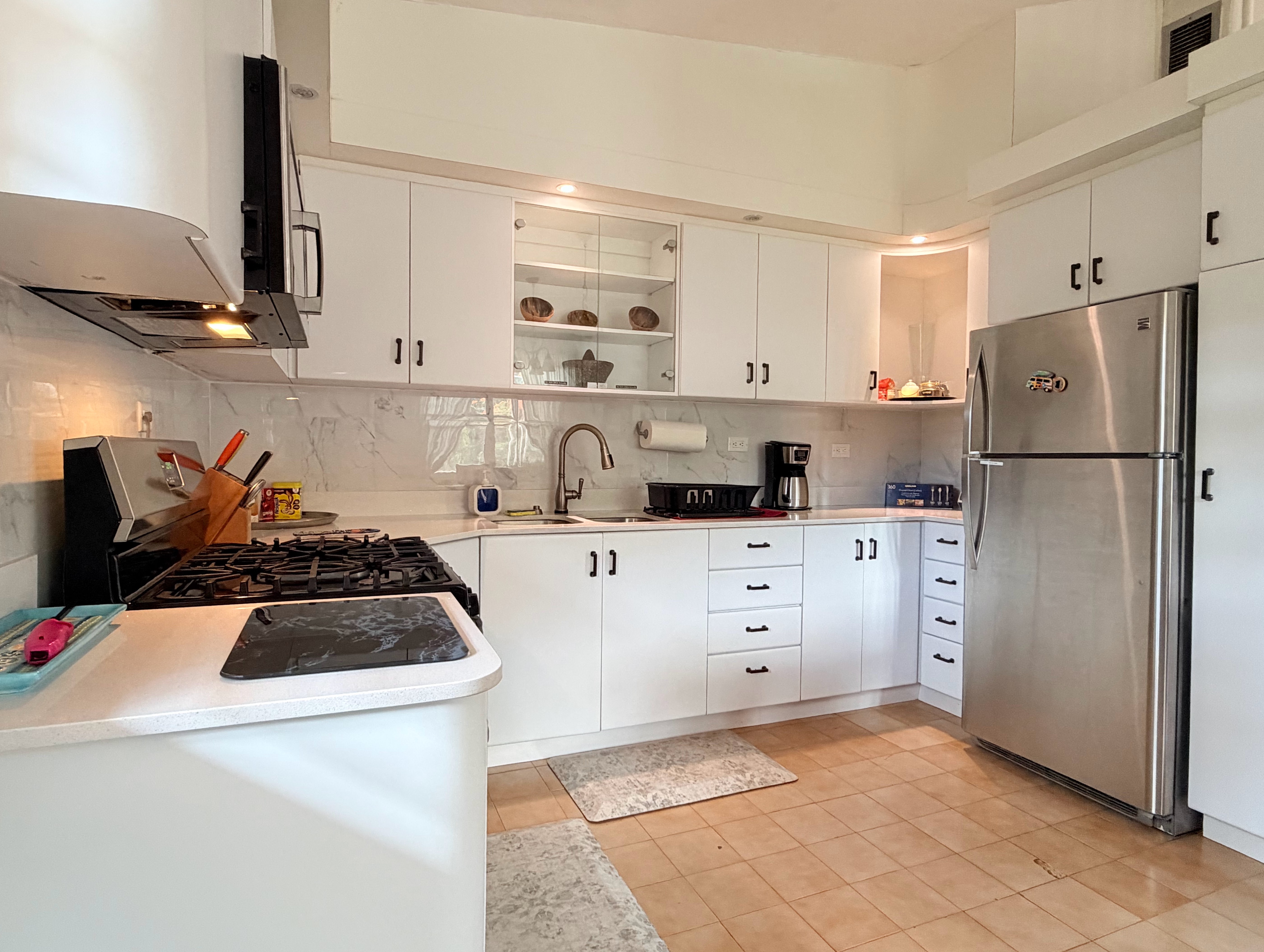 Bright modern kitchen with gas range, full fridge, and ample storage