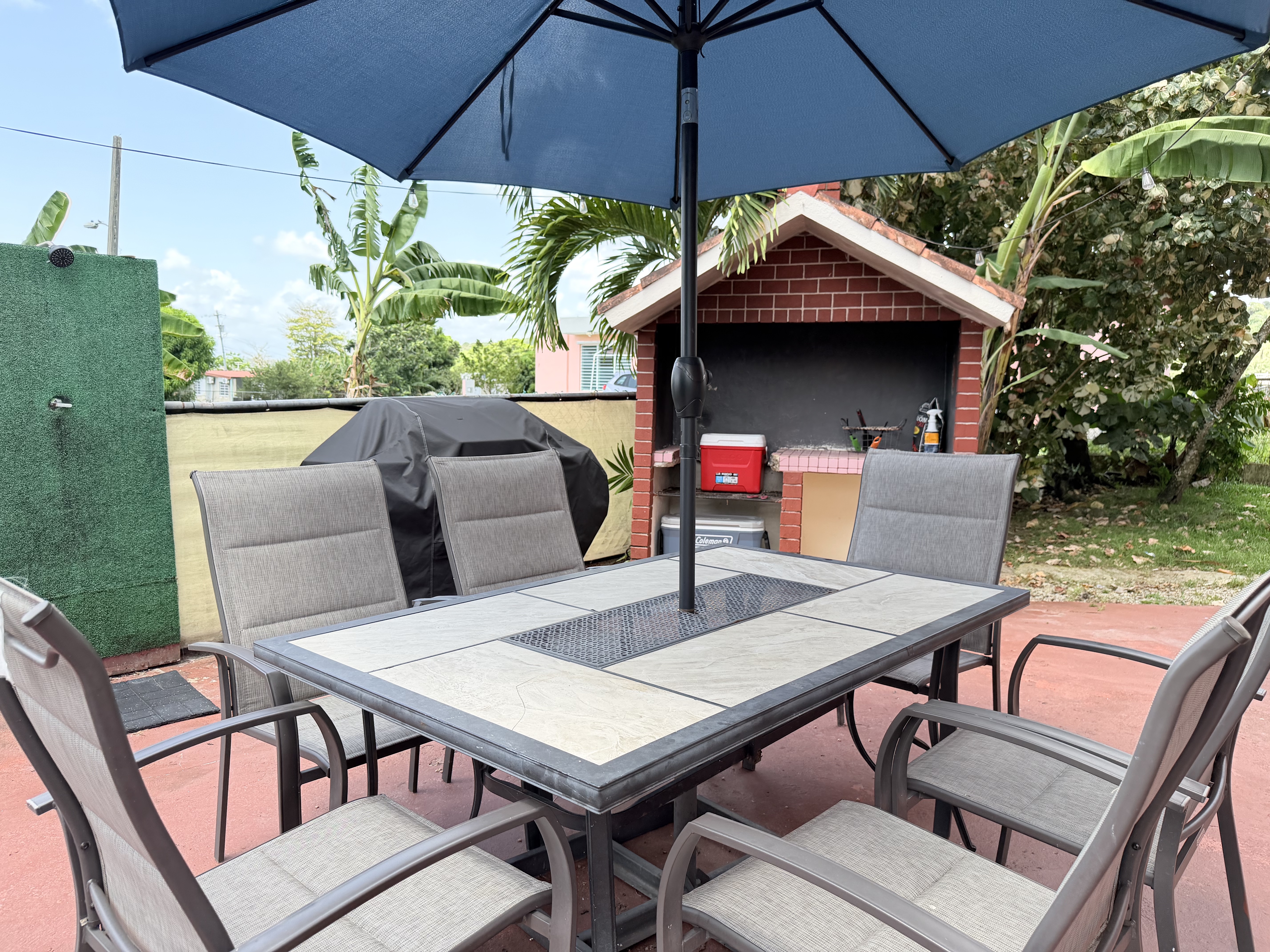 Shaded patio dining with BBQ area and tropical outdoor charm