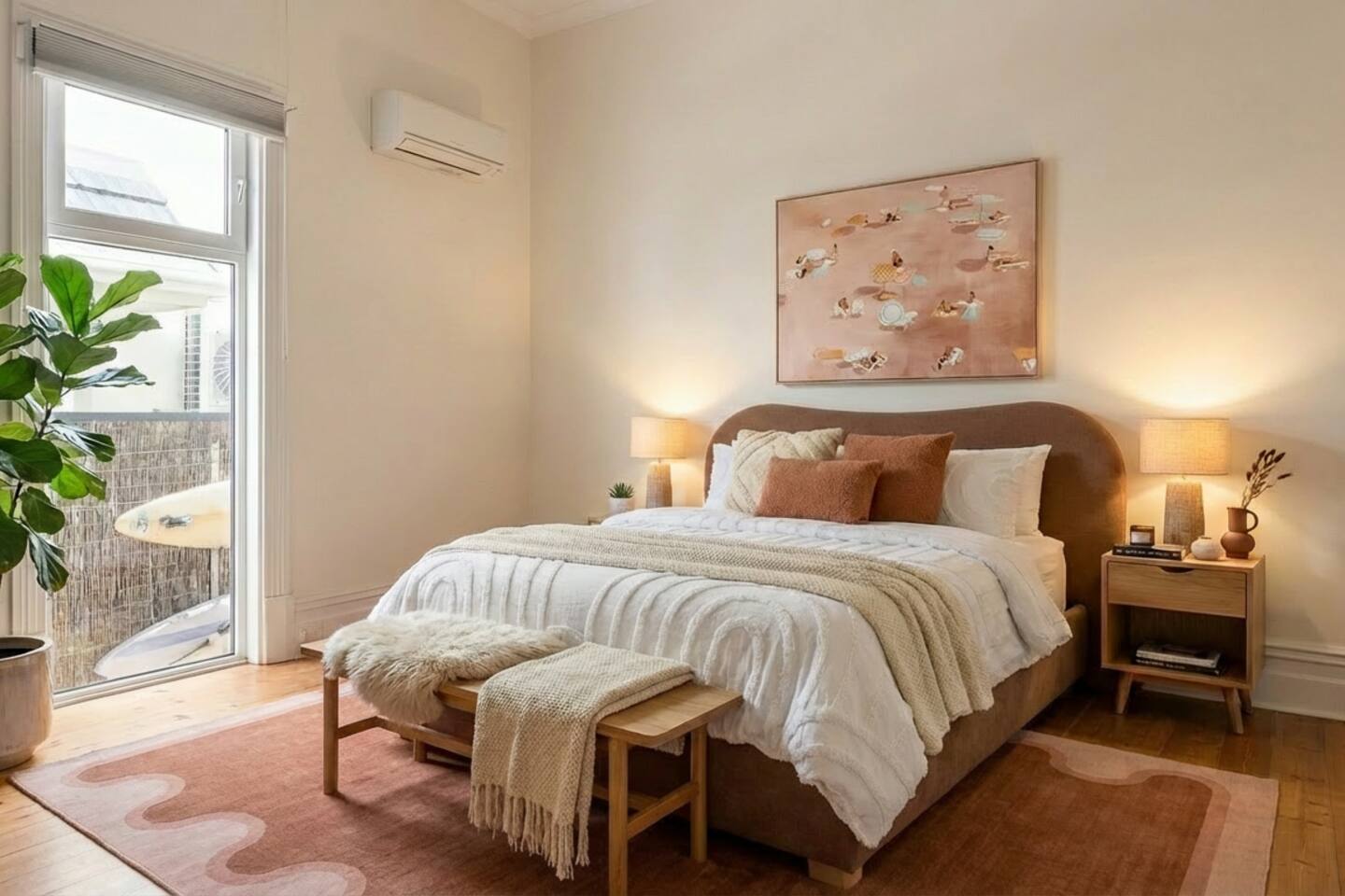 King bedroom with curved timber bed and coastal artwork