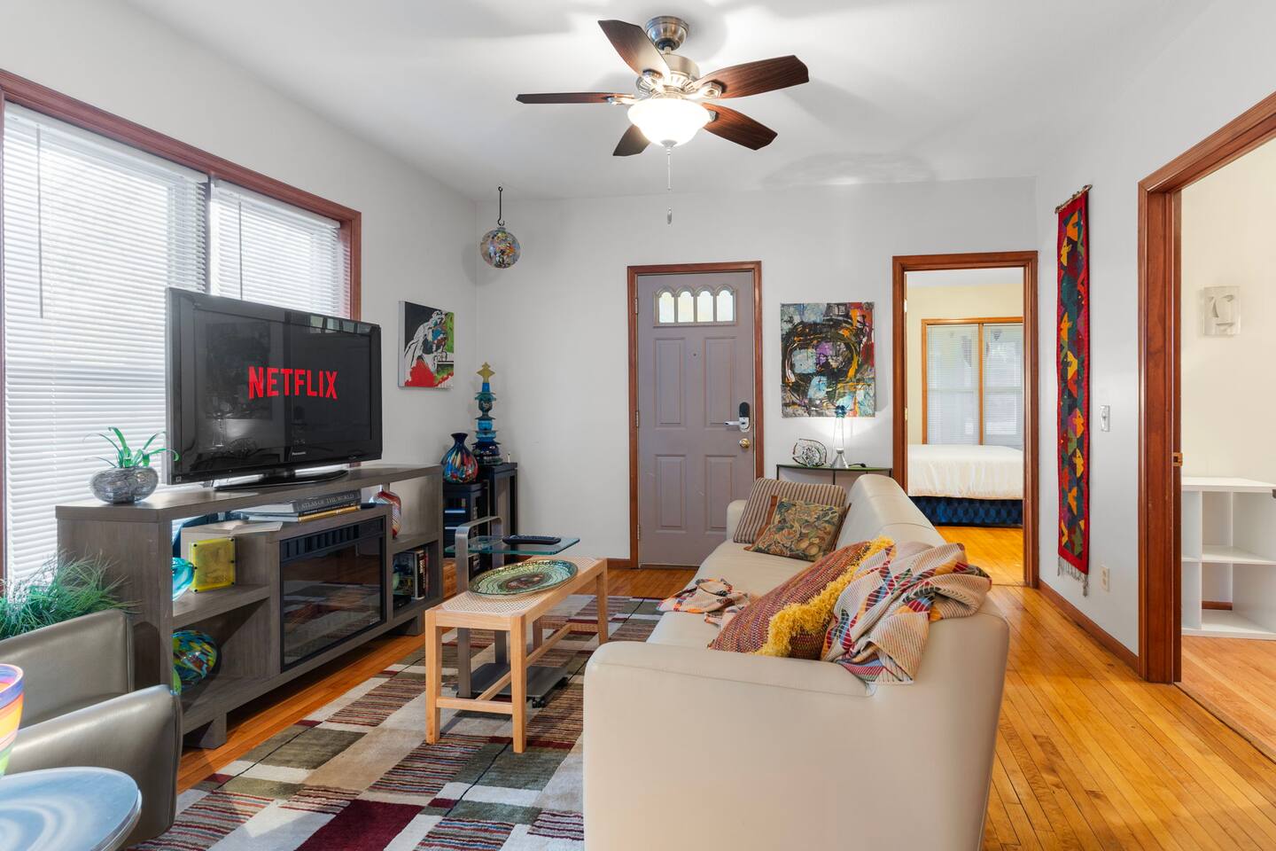 A bright and cozy living room with a comfy sofa, colorful pillows, and a Smart TV with Netflix perfect for relaxing.
