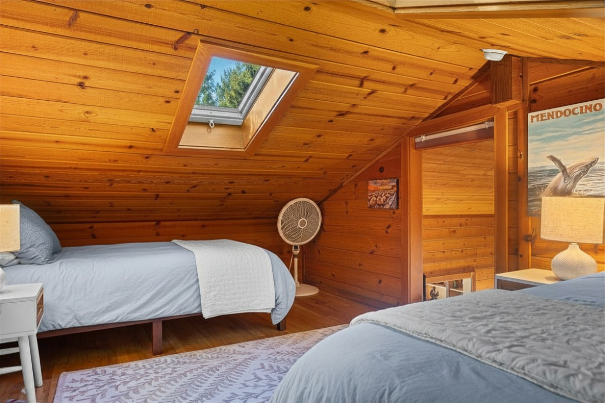 Cozy wood loft with twin beds, skylight, and warm ambient lighting