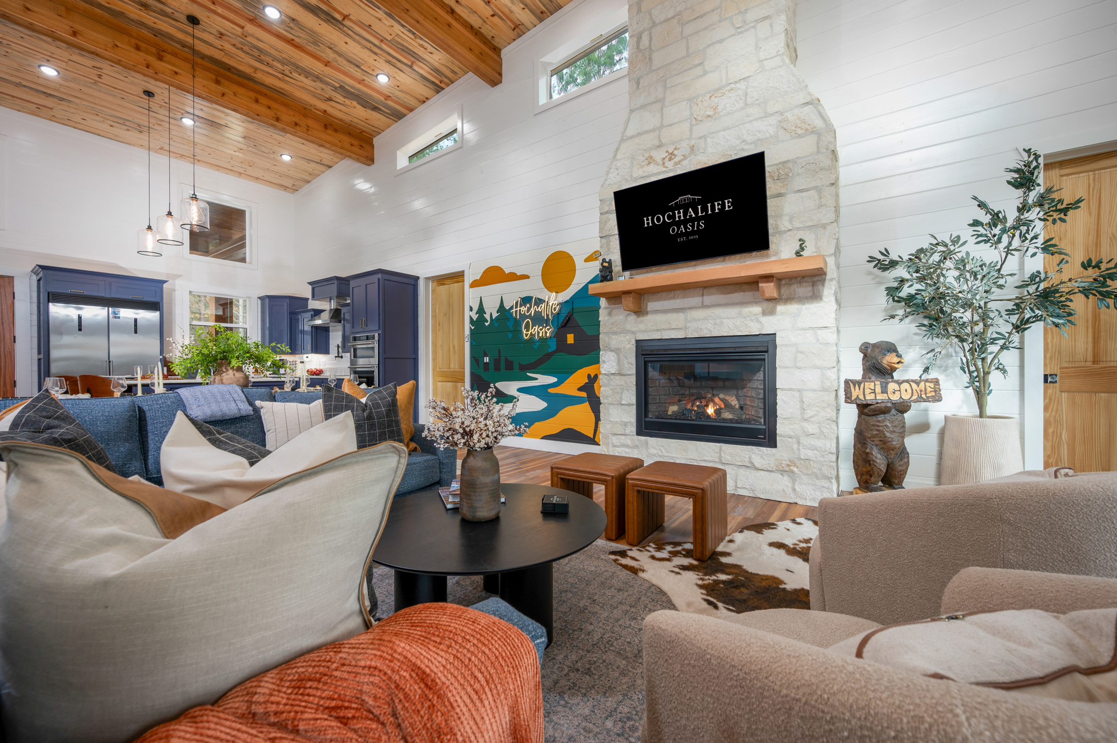Vaulted great room with stone fireplace, cozy seating, and cabin charm