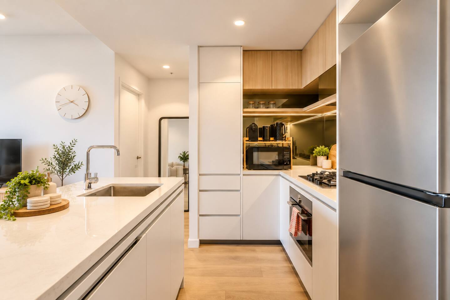 Clean white kitchen counter w/ sink & sleek cabinetry.