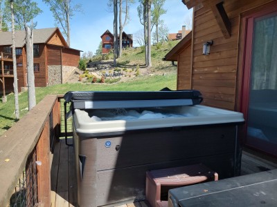 Private deck hot tub with wooded hillside views at rustic cabin retreat