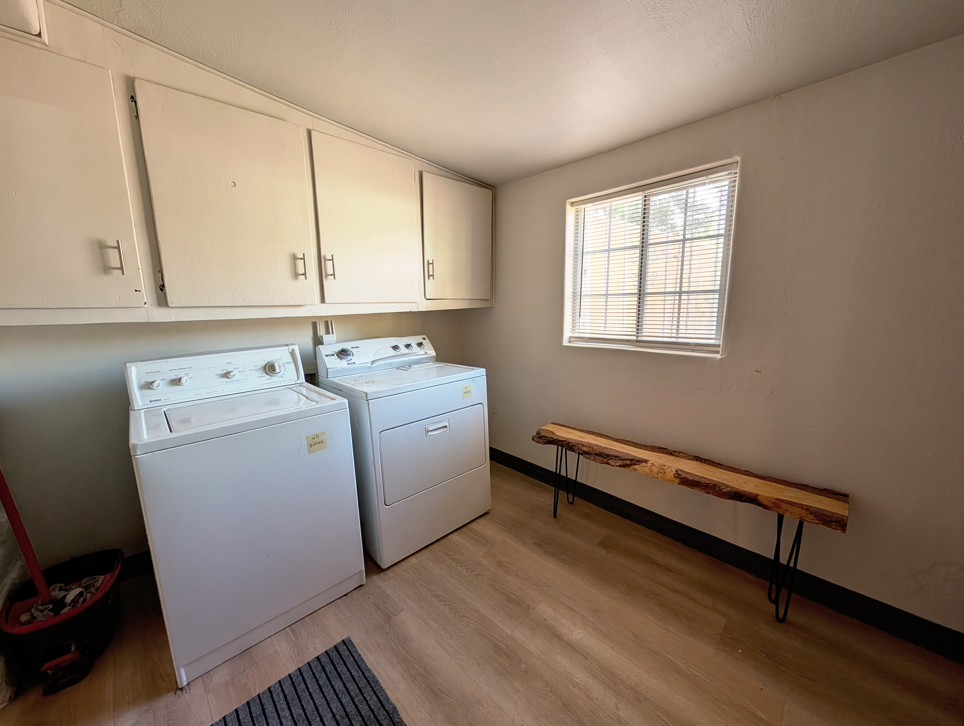 Bright laundry room with full-size washer/dryer and rustic folding bench