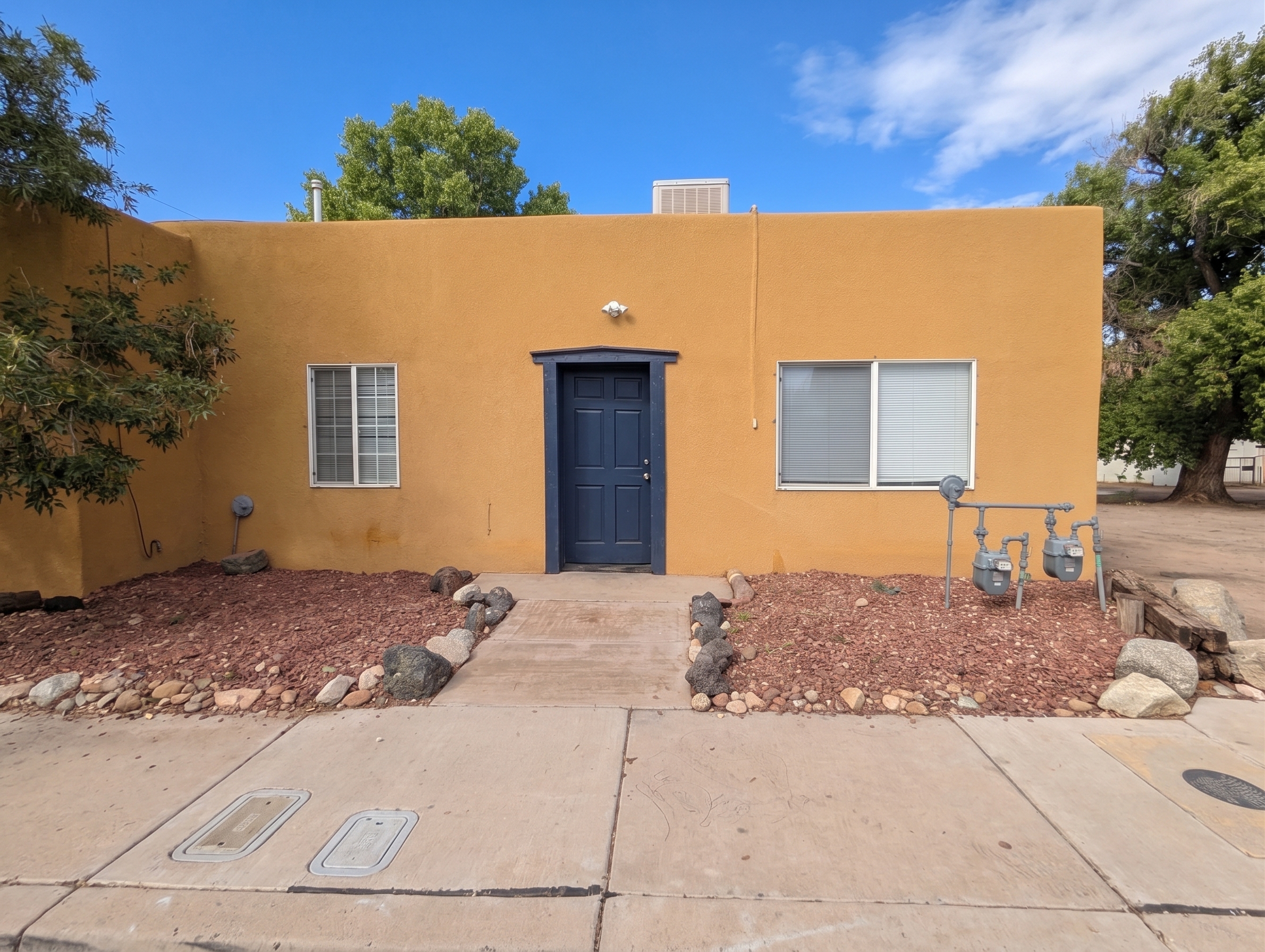 Charming Southwestern entry with bold blue door and desert landscaping