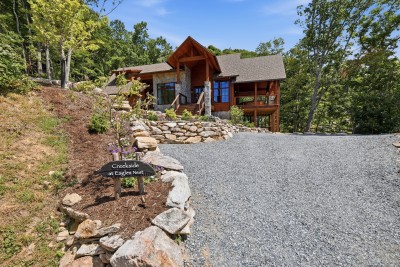 A gravel drive winds through the hardwoods to this timber-and-stone retreat, its covered entry and gabled roofline announcing the mountain getaway that awaits at Creekside at Eagles Nest.