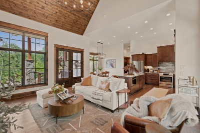 Take in the open flow from the sitting area through to the kitchen and dining nook — layered rugs, leather and linen seating, and a stocked bar cart set the scene for easy togetherness.