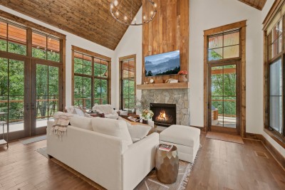 Floor-to-ceiling glass doors flank the stacked-stone fireplace in this vaulted living room, opening on both sides to the deck for a space that blurs the line between indoors and out.