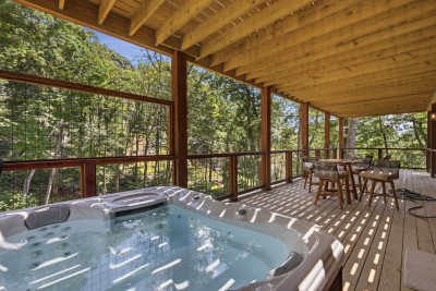Slip into the covered hot tub as dappled sunlight filters through the treetops, then dry off at the adjacent bistro table overlooking a private, wooded ravine — the perfect outdoor retreat.