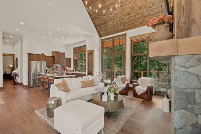 Barstool seating lines the kitchen island just steps from the living area, where glass doors open onto the deck and a wall of windows brings the surrounding hardwoods right into the room.
