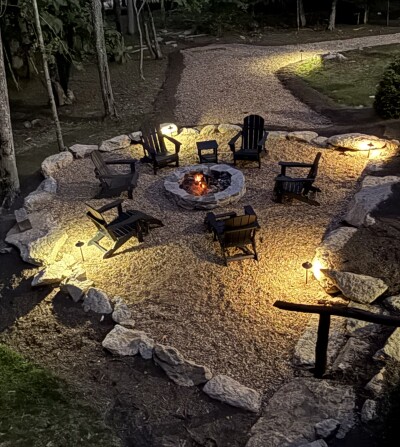 Cozy illuminated fire pit lounge nestled in a peaceful wooded setting