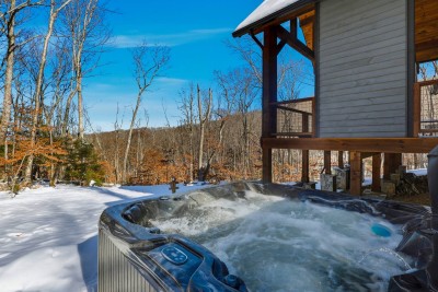 This private hot tub area offers the ultimate place to relax after a day in the mountains, tucked beside the cabin with peaceful forest surroundings and easy access from the home.