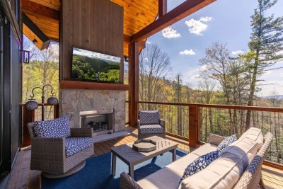 Relax on this covered mountain deck with plush seating, a stone fireplace, and peaceful forest views. It is the perfect spot for morning coffee, evening wine, or cozy nights enjoying the fresh air year-round.