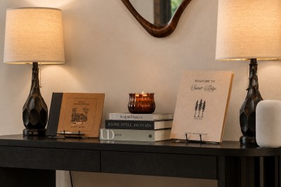 Step inside to a warmly lit entry table styled with curated decor, a stack of designer books, and a personalized Sunset Ridge guest book and welcome guide waiting just for you — the first sign this stay was made to feel like yours.