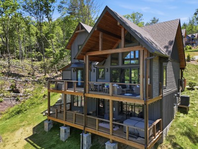 Modern mountain cabin featuring covered decks and stunning wooded views — a beautifully appointed retreat perfect for relaxing outdoors and soaking in the peaceful natural surroundings throughout your stay.