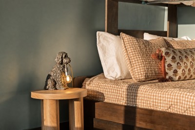 Tucked-away bunk nook with a dark rustic wood frame, warm plaid gingham bedding, and playful touches like the whimsical bedside lamp — a favorite hideaway for kids (and kids at heart) after a big mountain day.