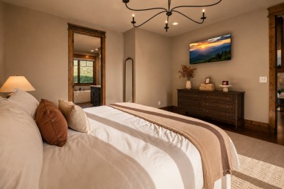 Retreat to the king suite, where rustic wood accents and an iron chandelier set a warm mountain tone. Step through the timber-framed doorway to your own private en suite, complete with a soaking tub for unwinding after a day on the trails.
