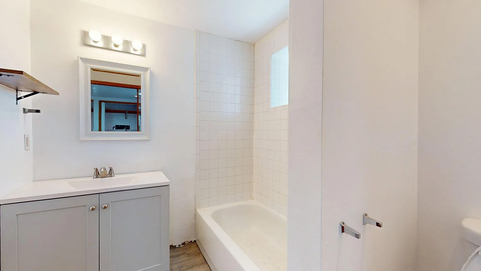 Bright bathroom with tub-shower combo and clean, simple finishes