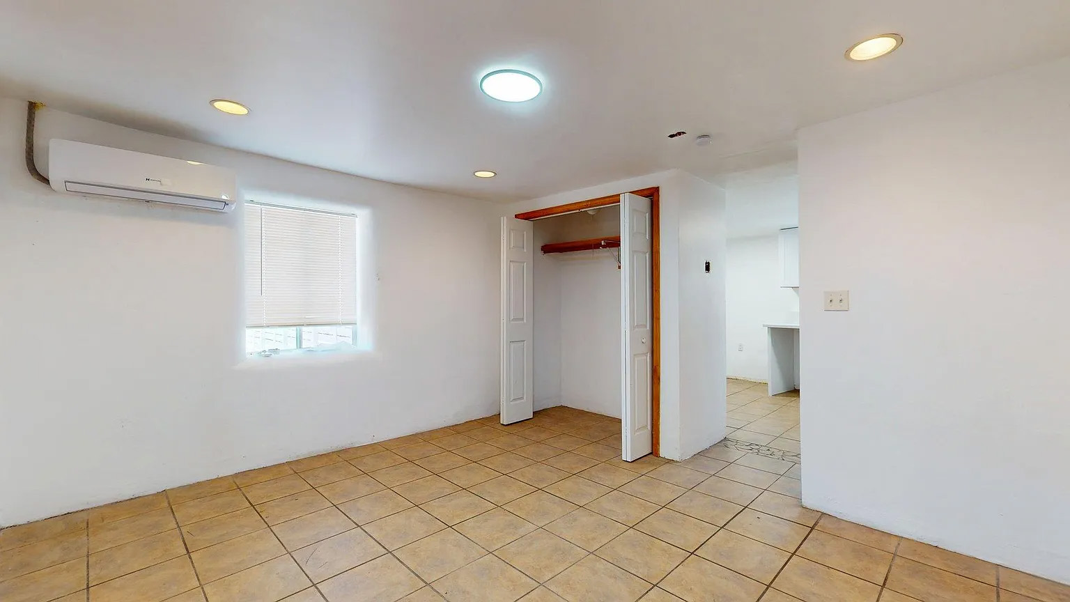 Bright tiled room with mini-split AC, natural light, and open closet