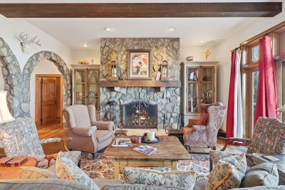 Gather in the heart of the home where a grand stone fireplace anchors the living space. Plush seating, rustic details, and warmth from the fire make this room perfect for cozy nights together.