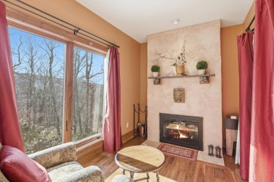 Curl up by the fireplace as sunlight pours in through tall windows. This cozy nook is perfect for reading, quiet conversation, or simply watching the changing light across the mountains.