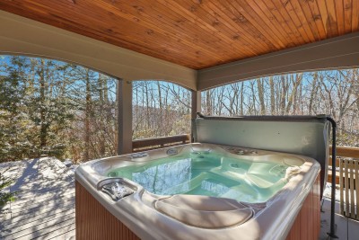 Relax in the hot tub beneath a wood-lined ceiling while nature surrounds you. Whether day or night, this sheltered space is ideal for unwinding in comfort no matter the season.