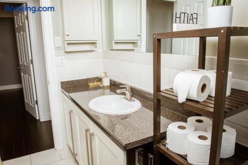 Bright bathroom vanity with granite counter and stocked storage shelf