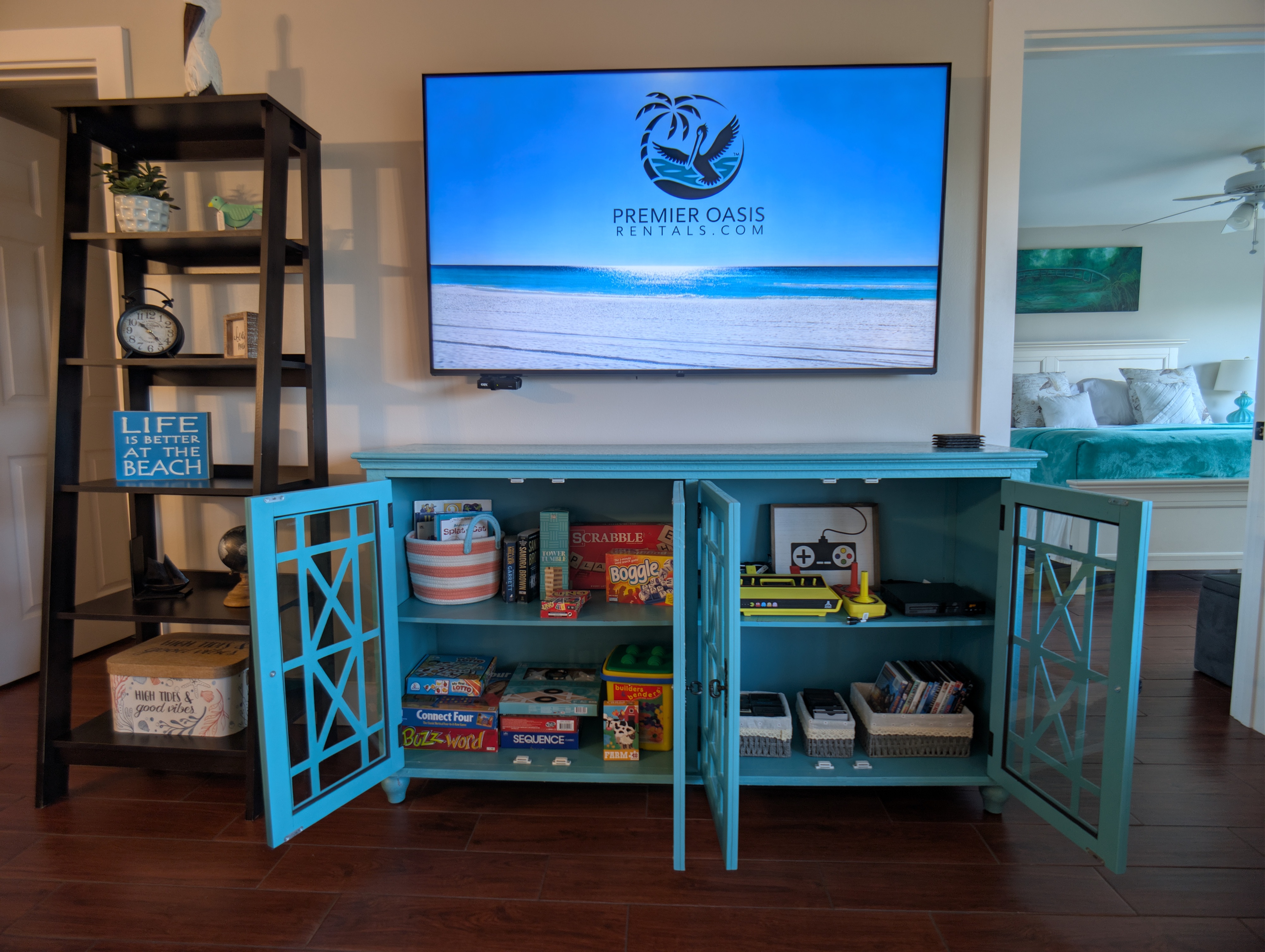 Family-friendly media hub with board games, books, smart TV, Atari game console, DVD,  and coastal decor.