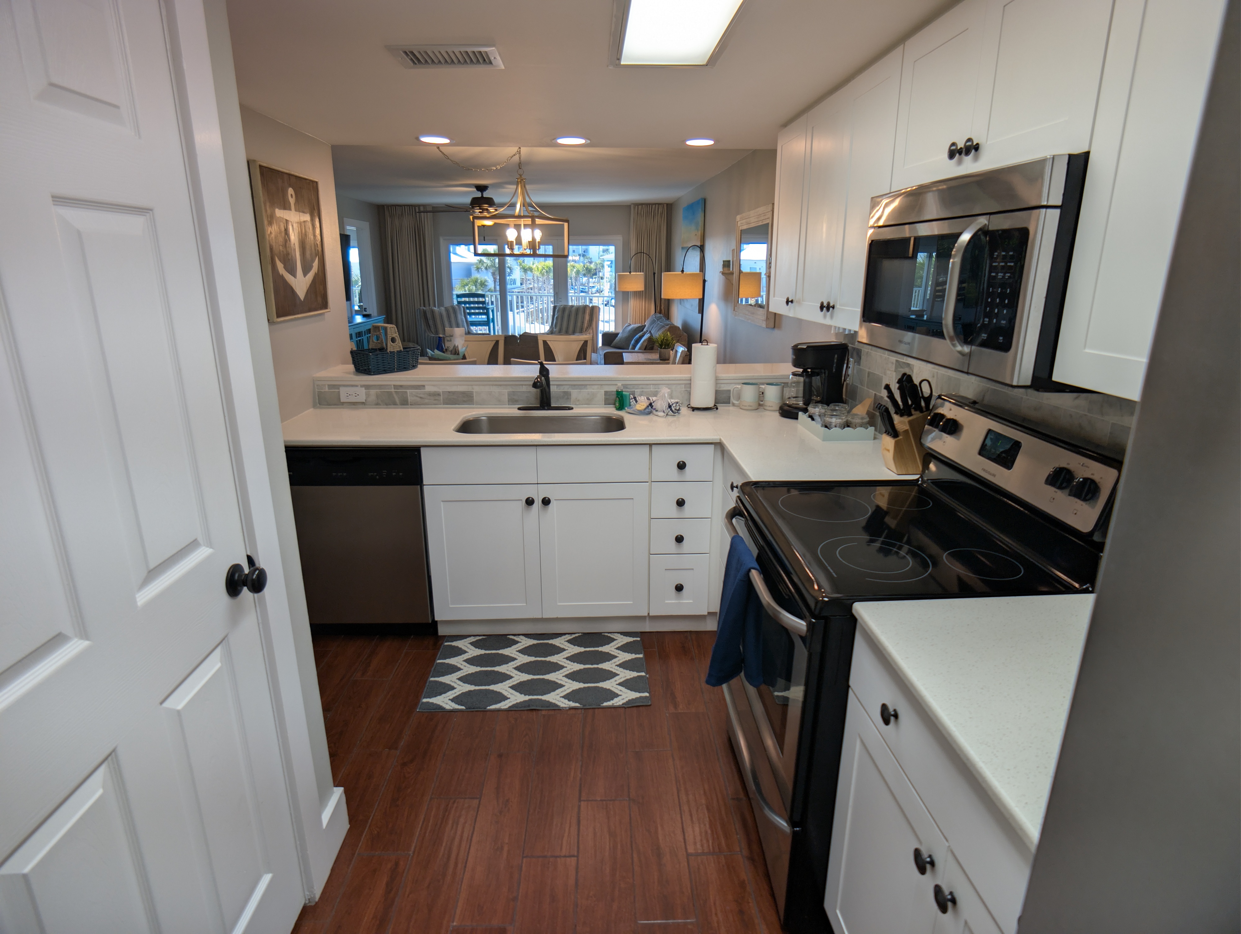 Sleek white kitchen, stainless appliances, open to dining with bright views.
