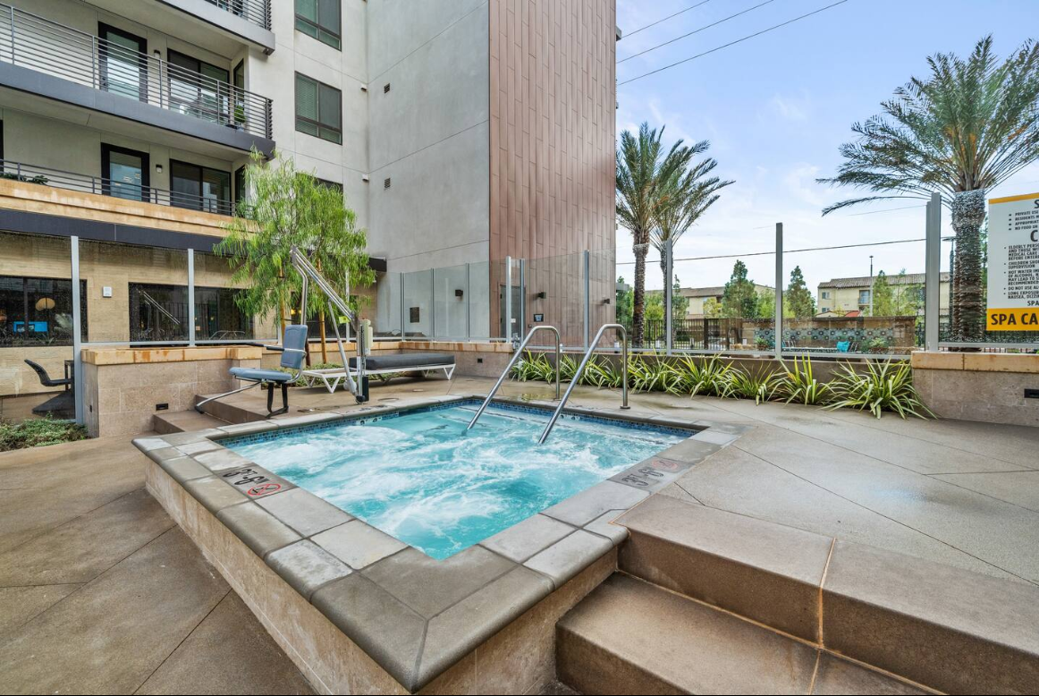 Resort-style outdoor hot tub with lounge seating and palm-lined deck