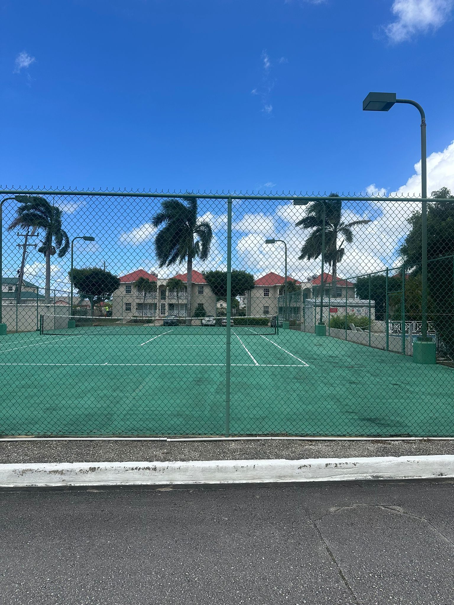 Tropical on-site tennis court with lights for day or evening play at the gated development Ixora - Crystal Court