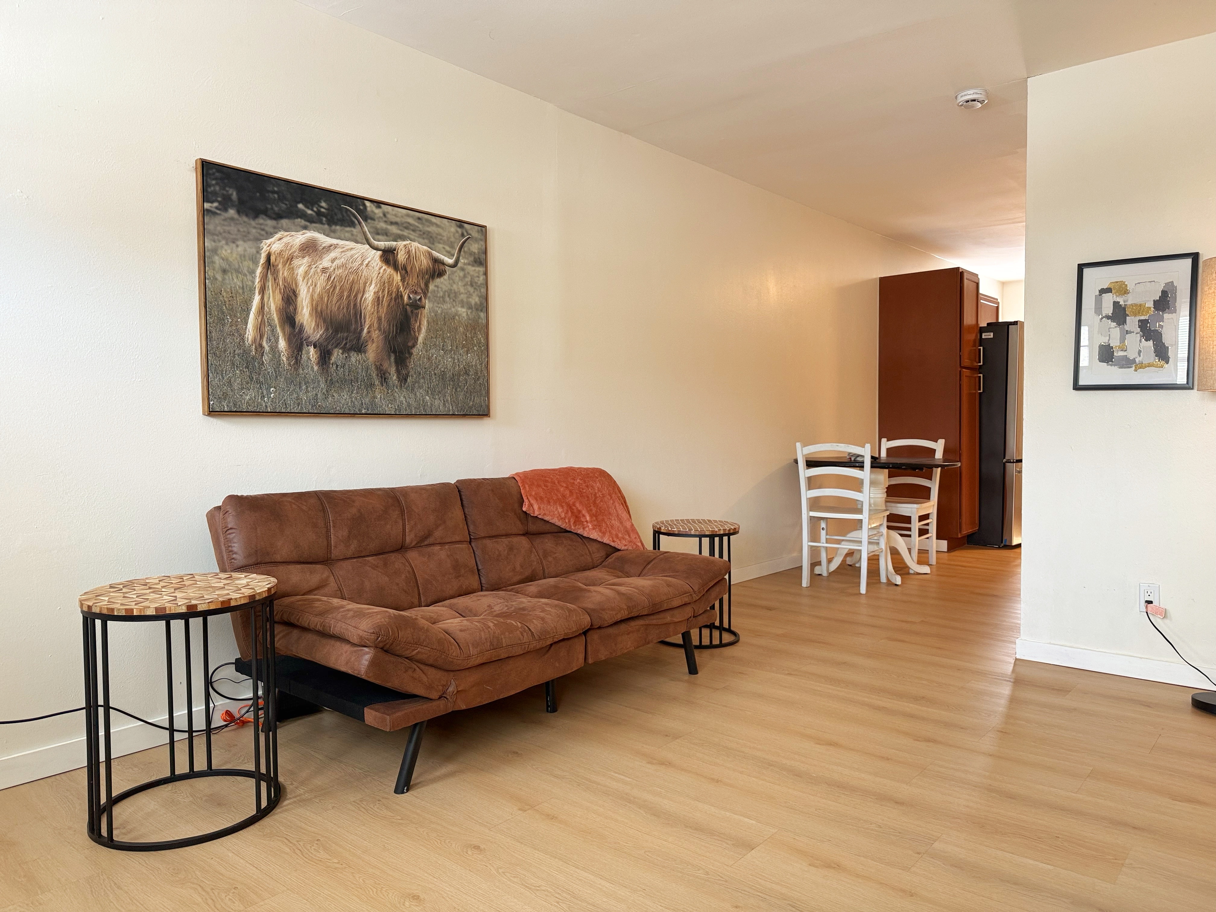 Light-filled lounge with suede sofa, wood floors, and dining nook.