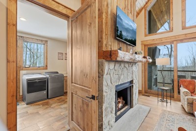 Warm up by the fireplace framed by rustic wood and stone. With a mounted TV above, it’s easy to settle in for a cozy evening indoors.