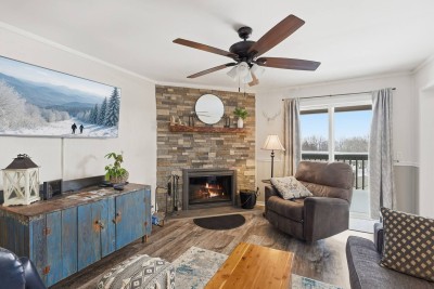 Relax in a warm and inviting living room featuring plush seating and a striking stone fireplace, ideal for cozy nights, movie marathons, or unwinding after a full day of mountain adventures.