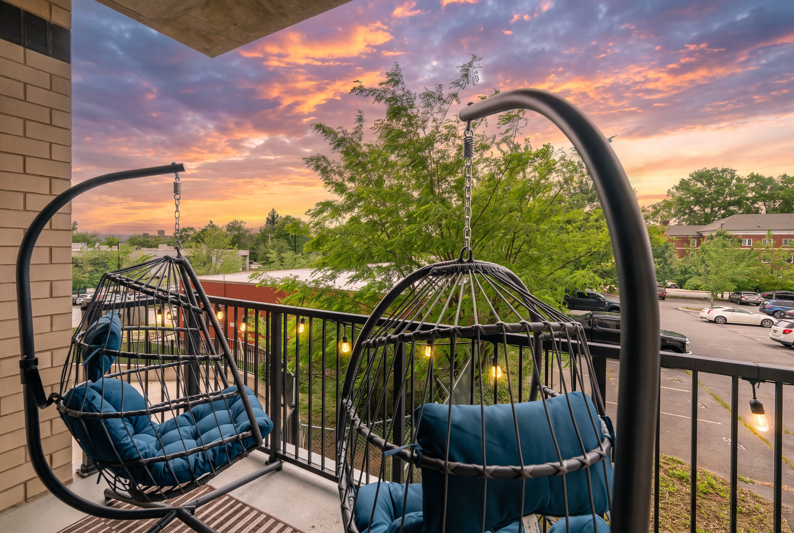 Sunset-view balcony with cozy hanging chairs and twinkling lights